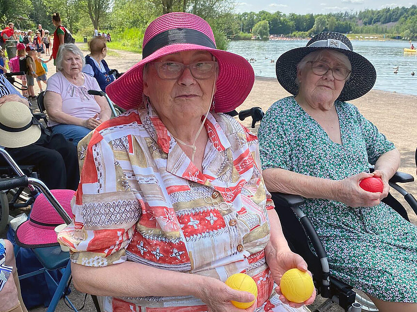 Deux résidentes en fauteuil tiennent des boules de pétanque dans leurs mains.