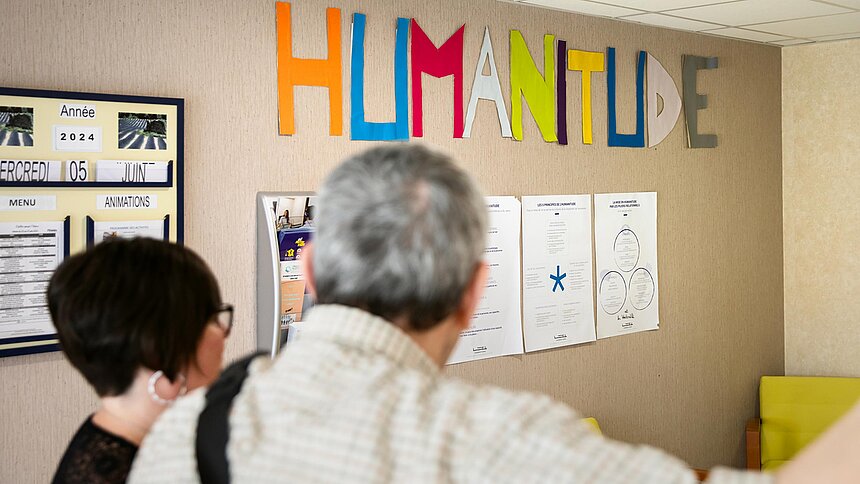 Deux personnes regardent un mur où il est écrit "Humanitude"