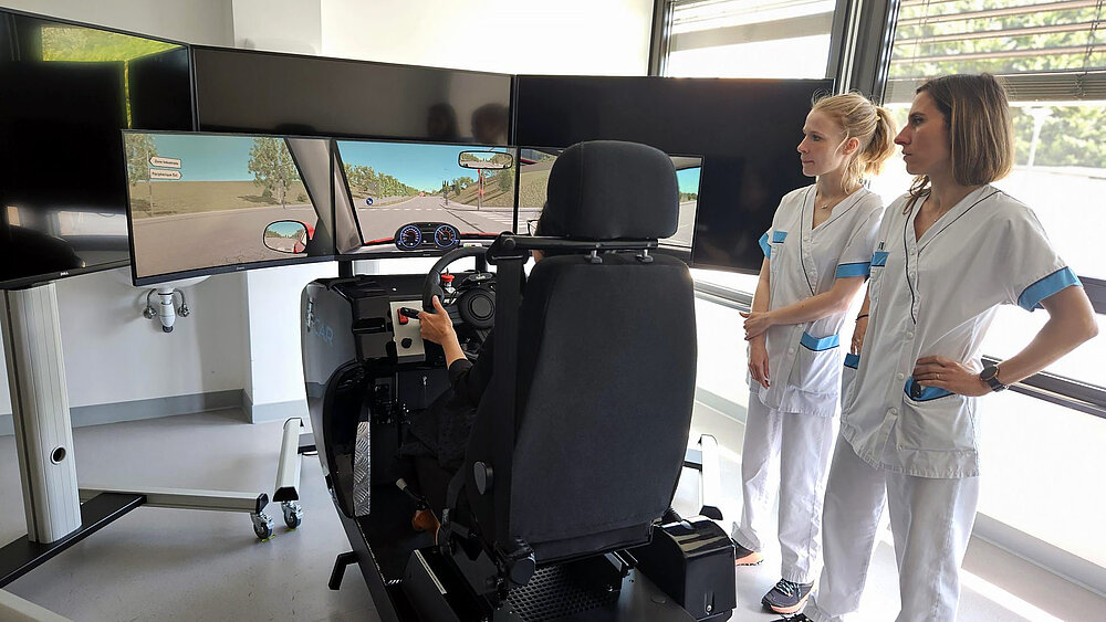 Une patiente teste le simulateur, sous le regard de deux professionnelles Filieris