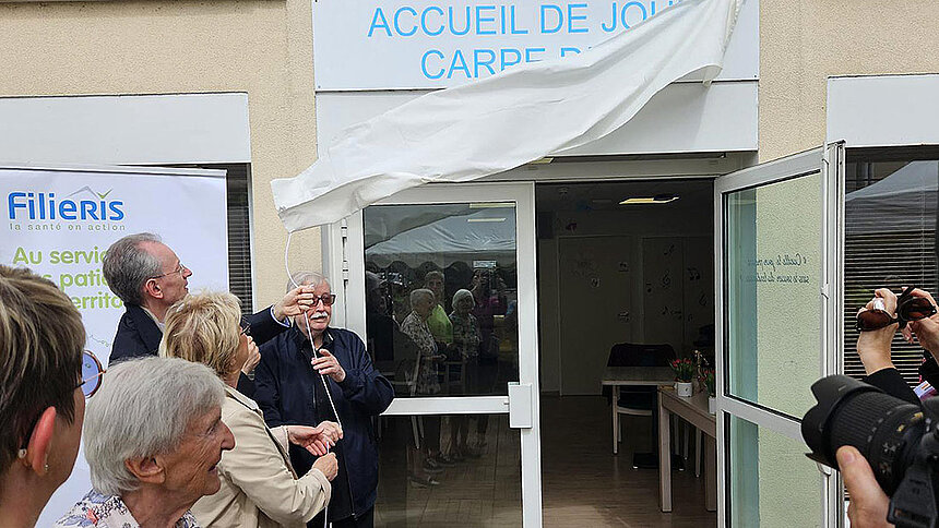 Gilles de Lacaussade dévoile la plaque d'accueil de jour devant les participants.