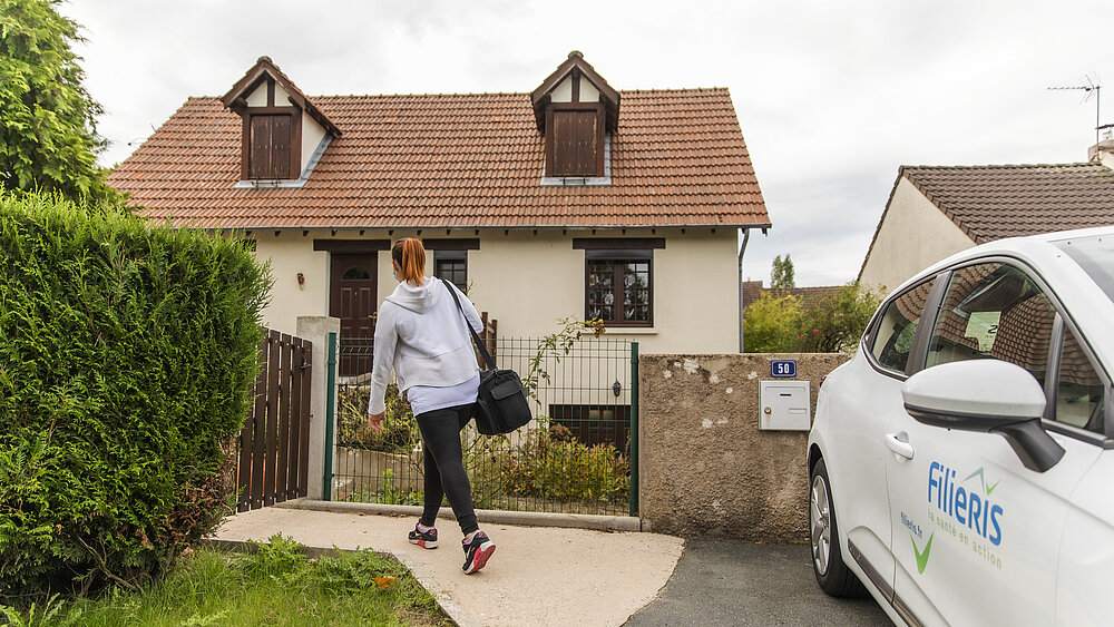 Une aide à domicile Filieris sort de sa voiture pour se rendre dans la maison d'un patient