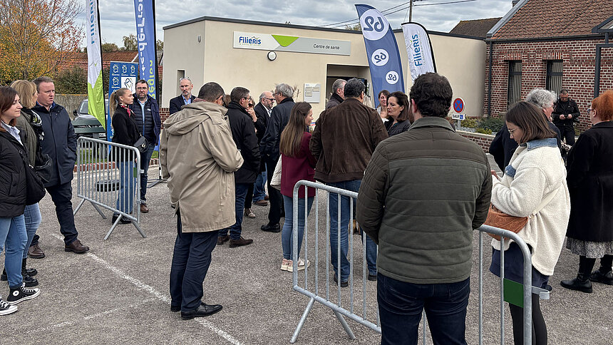 Les invités sont réunis à l'extérieur devant l'entrée du centre de santé.