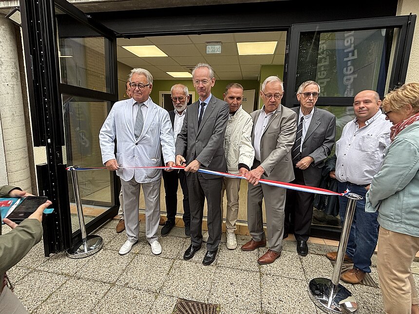 Un groupe de personnes se tient devant l'entrée du centre de santé. Gilles de Lacaussade, directeur général de Filieris et Alain Lefevre, maire d'Aix-noulette, découpent le ruban d'inauguration.